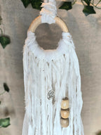 Valkoinen noitakello, jossa puuhelmiä, hopeisia kelloja, pentagram riipus ja kuukivi.