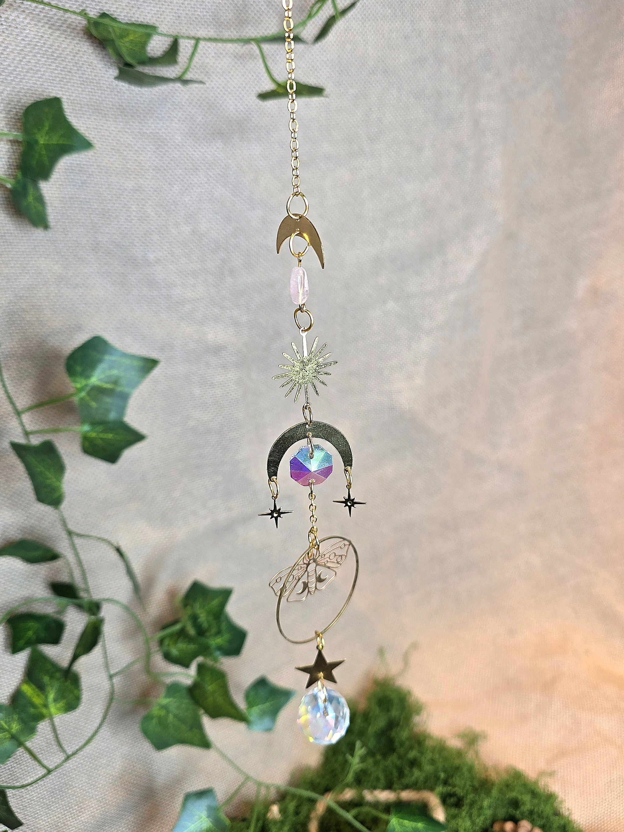 Aurinkosieppari, jossa kuu, ruusukvartsi, aurinko, tähti ja perhonen symboit.