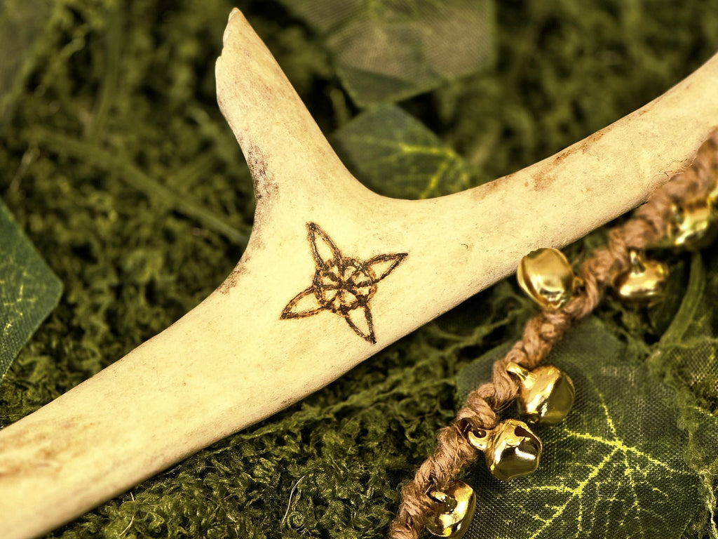 Porosarvesta valmistettu rituaalisoitin, kultaiset kellot, pentagram, noidansolmu ja kuusymboli.