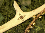 Porosarvesta valmistettu rituaalisoitin, kultaiset kellot, pentagram, noidansolmu ja kuusymboli.