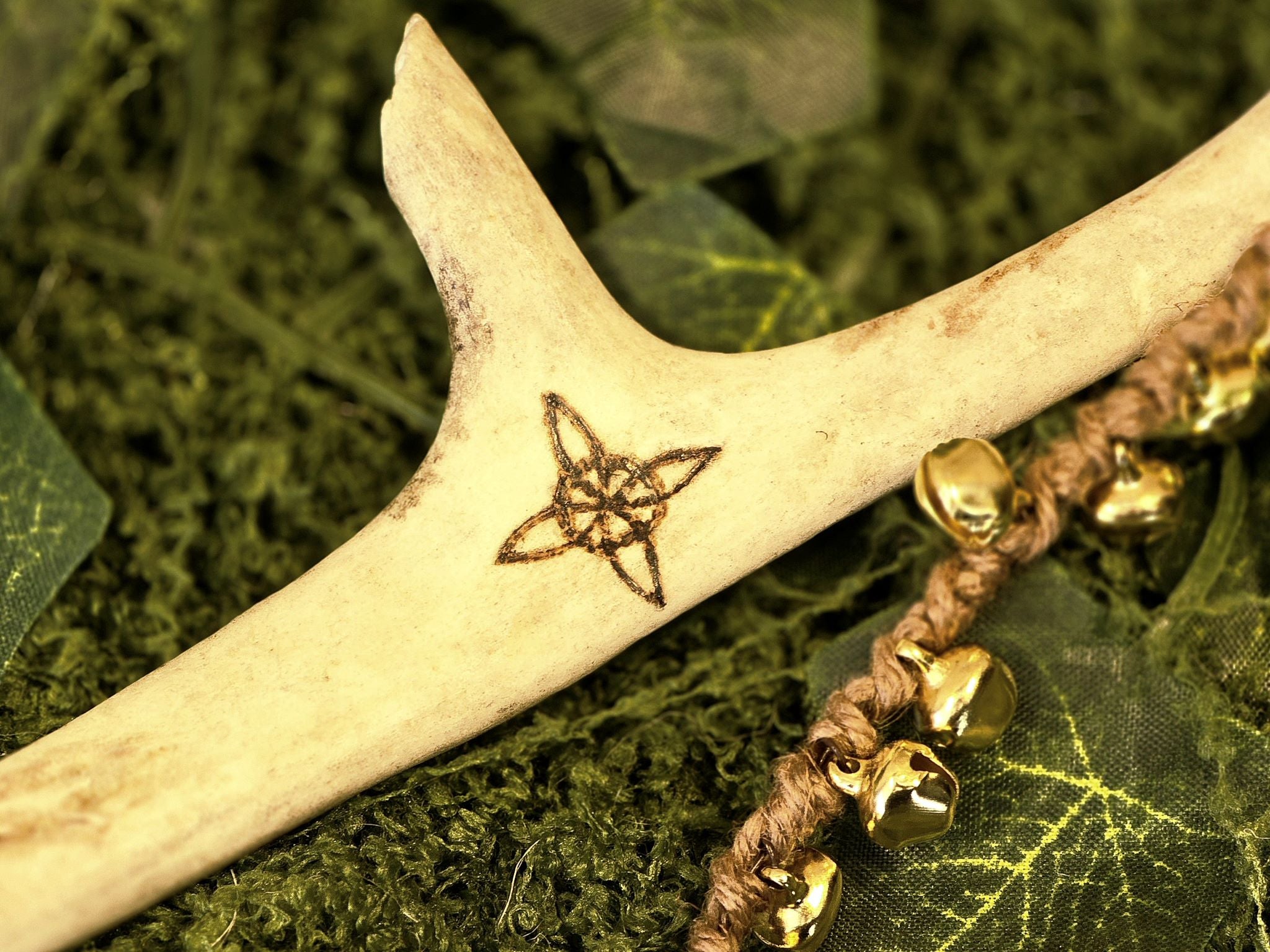 Porosarvesta valmistettu rituaalisoitin, kultaiset kellot, pentagram, noidansolmu ja kuusymboli.
